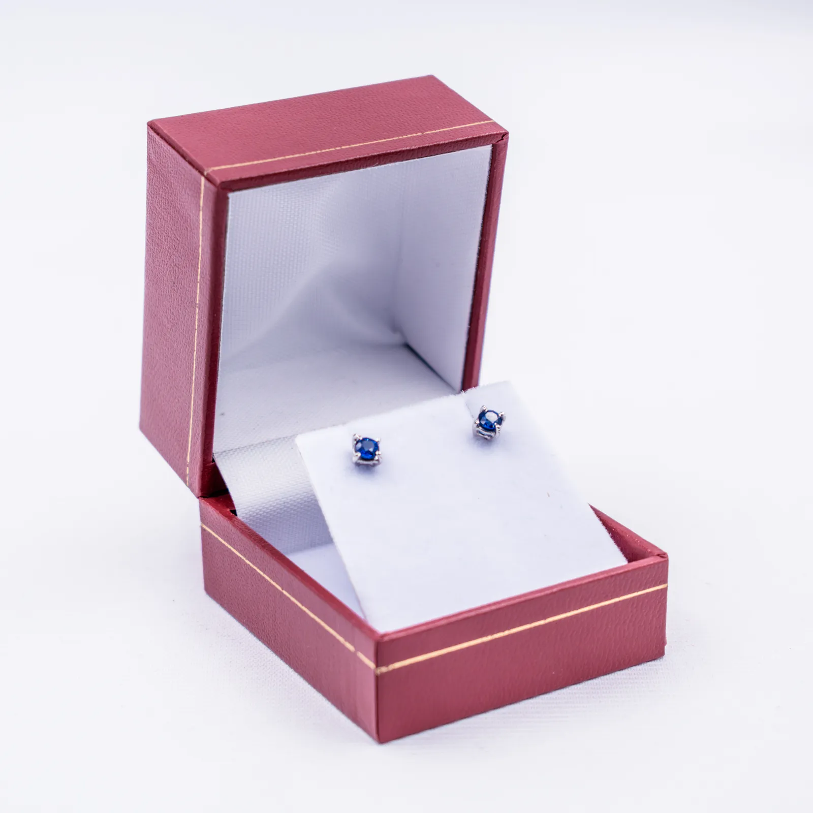 Aretes de zafiro azul en una caja de joyería roja