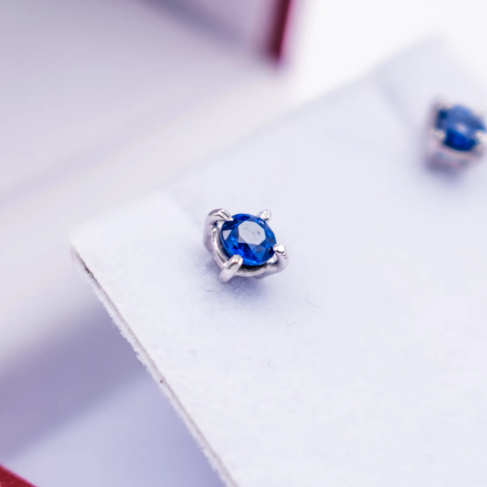 Detalle macro de aretes con piedras azules sobre una superficie blanca