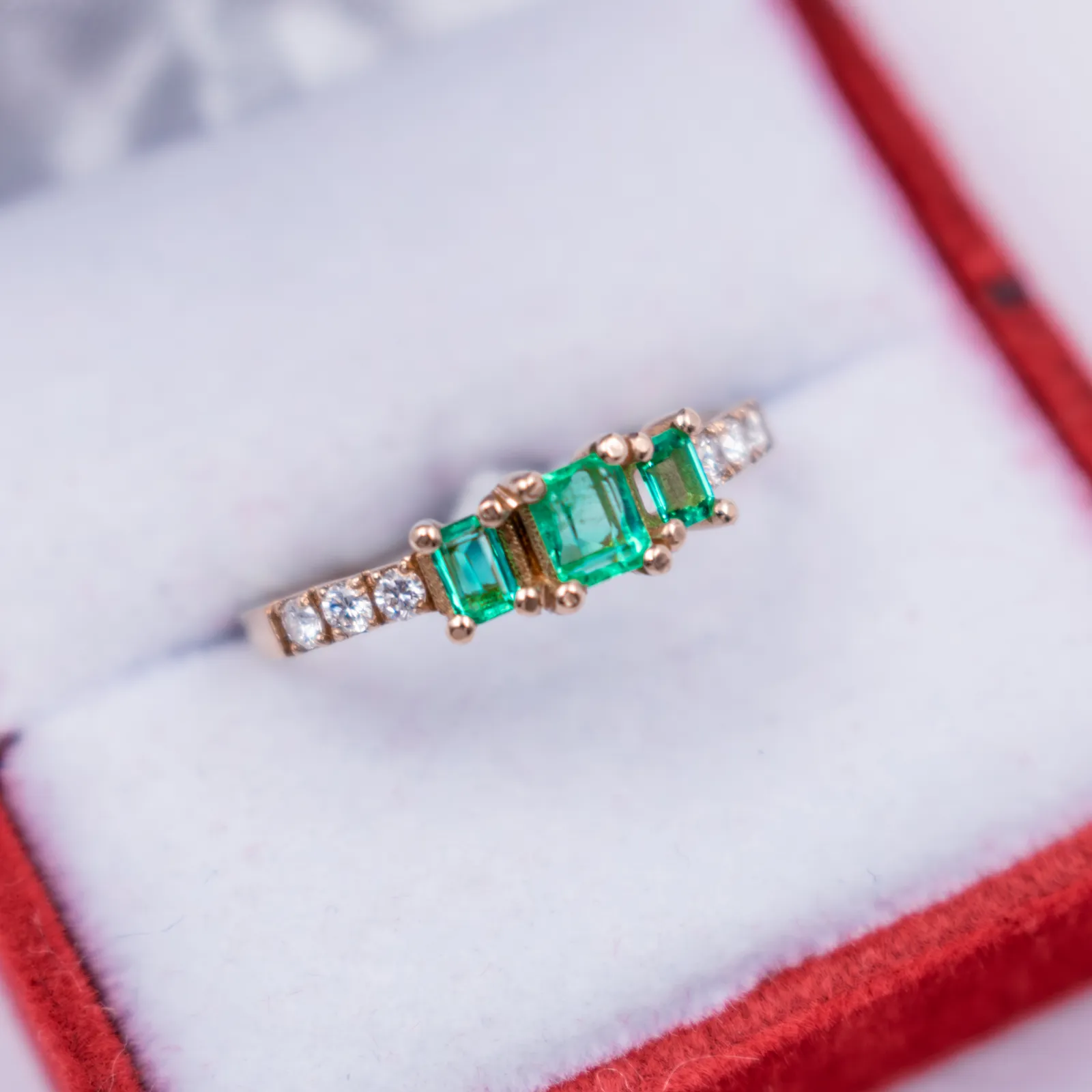 Anillo de oro con esmeraldas y diamantes en caja de terciopelo rojo