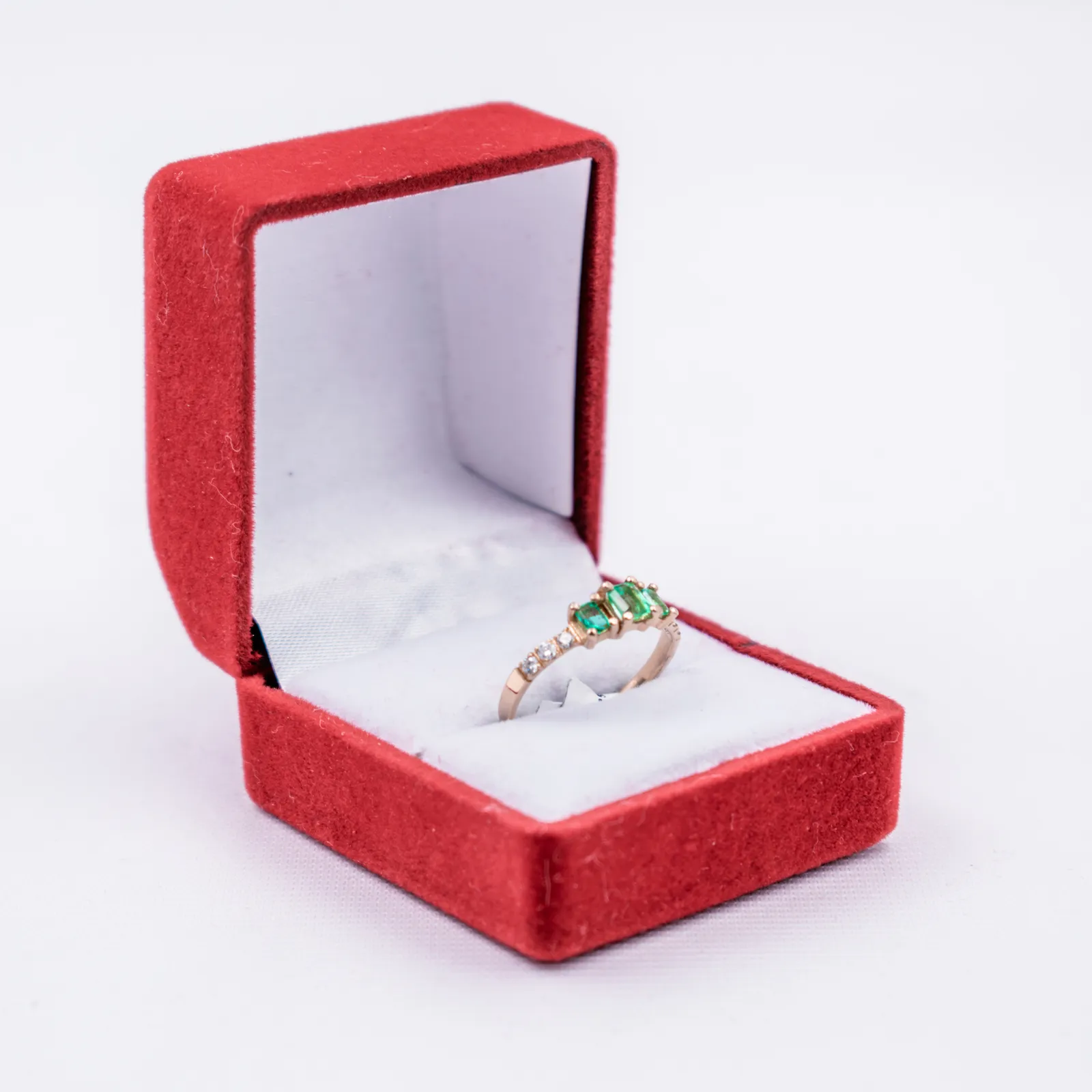 Anillo de esmeraldas en una caja de joyería de terciopelo rojo