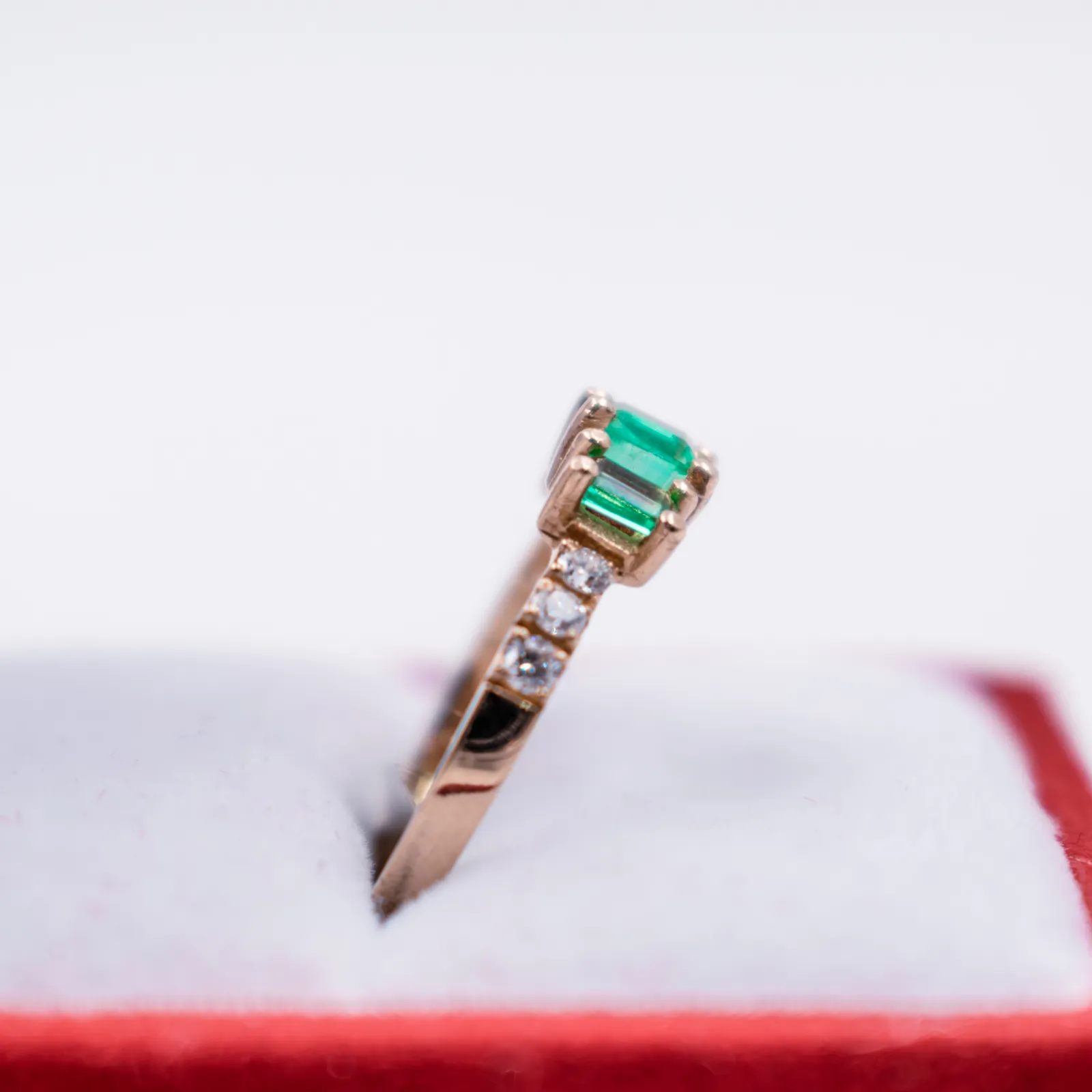 Detalle lateral de un anillo de oro con esmeraldas y circones