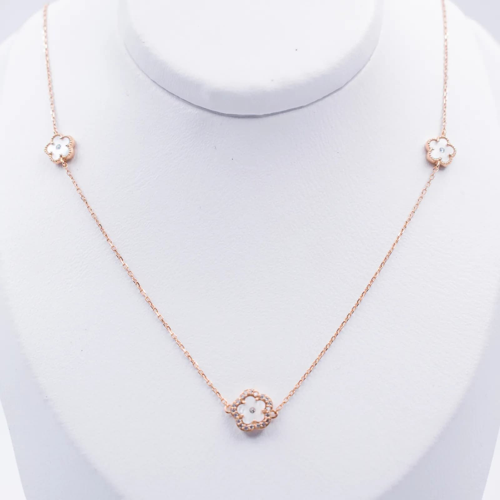 Collar de oro con dijes de flor exhibido en un busto de joyería