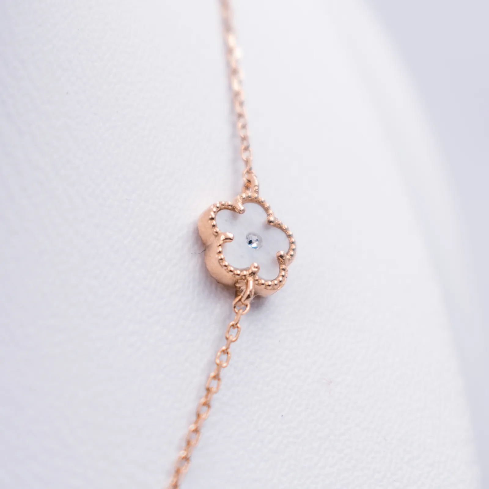 Detalle de una pulsera de oro con dije de flor y nácar