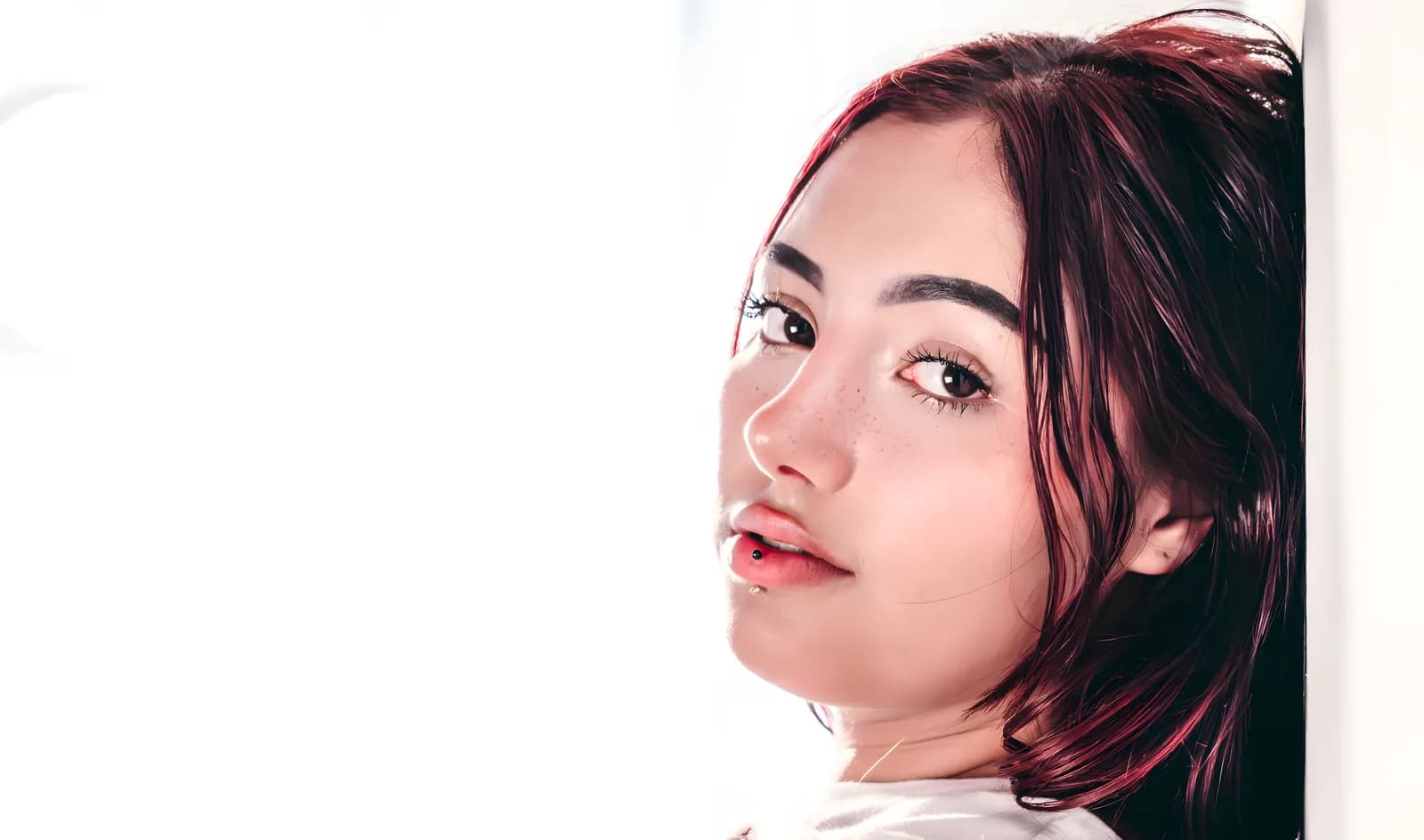 Primer plano de estudio de una mujer joven con cabello rojizo sobre fondo claro