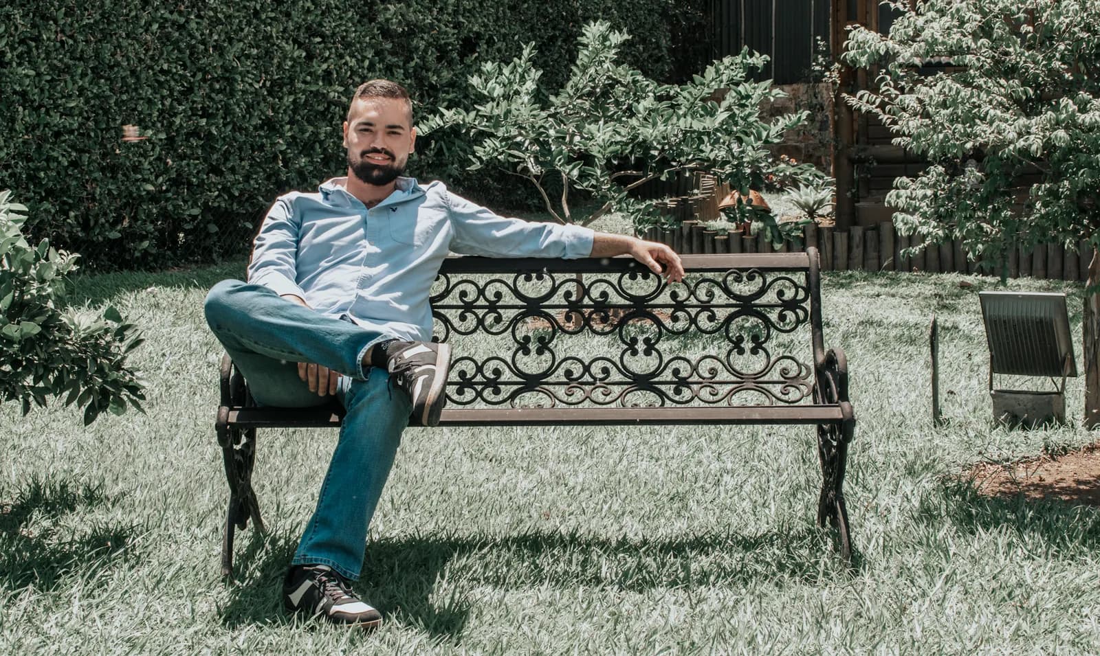 Retrato de un hombre sonriente sentado en una banca de jardín