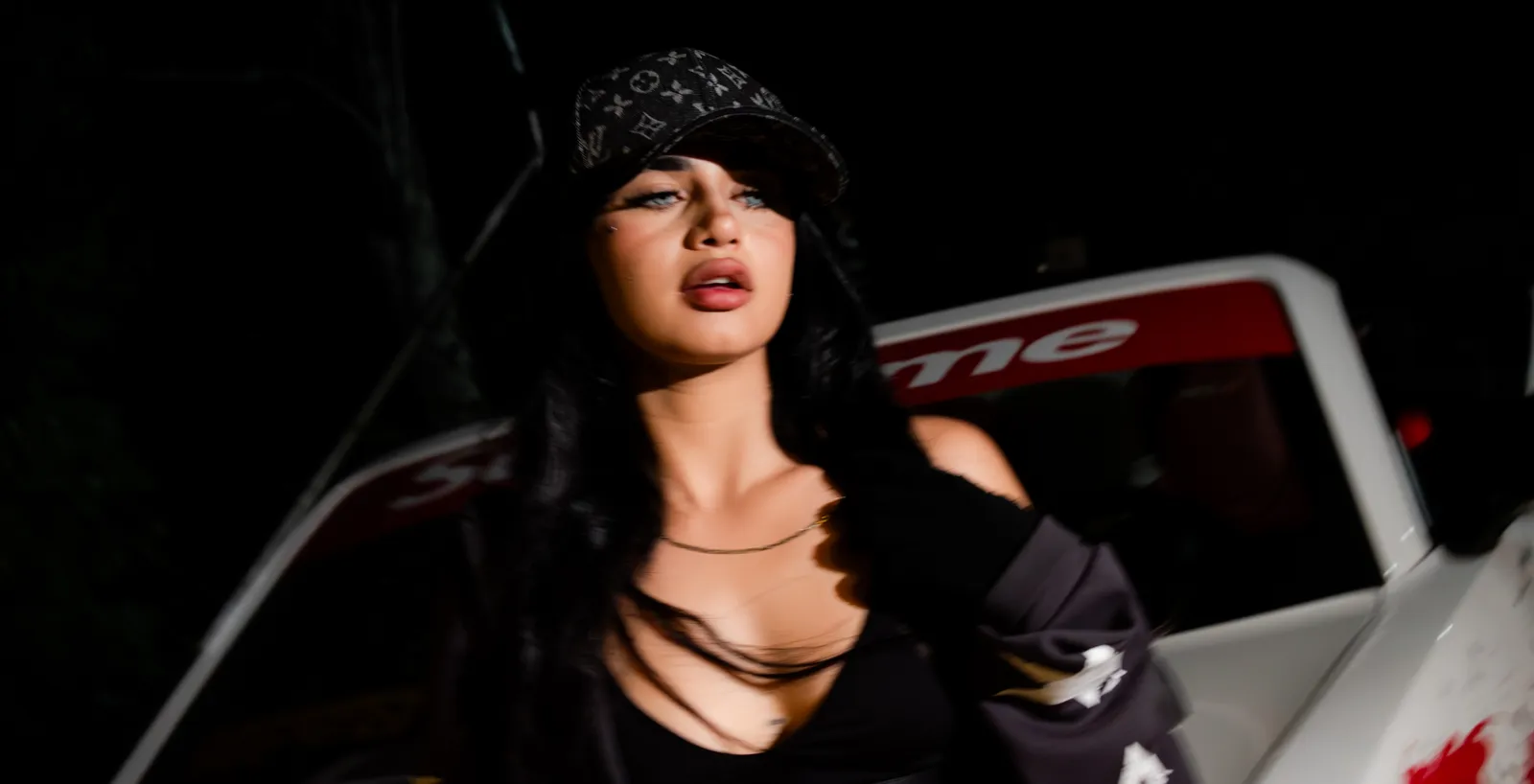 Retrato nocturno con flash de una mujer con gorra y cadena dorada